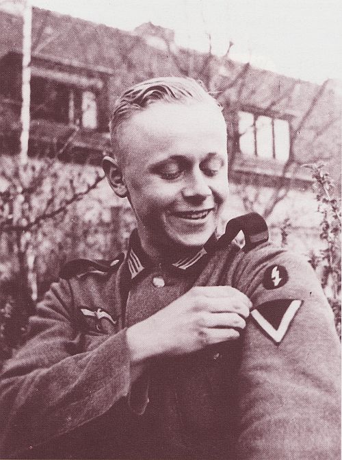 A smiling man in uniform adjusts his jacket, exuding confidence and professionalism. Peter Kollwitz